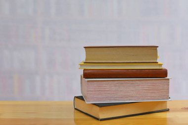 Kütüphanedeki ahşap masada yığınla kitap.