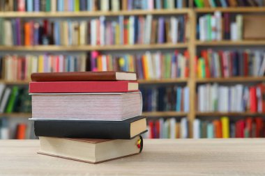 Kütüphanedeki ahşap masa üzerine kitap yığını, metin için kopyalama alanı.