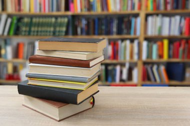 Ahşap masanın üzerinde bulanık arka plana karşı bir yığın kitap. Okula dön, boşluğu kopyala