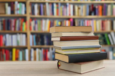 Kütüphanedeki ahşap masada yığınla kitap.