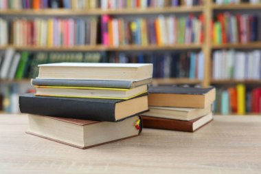 Kütüphanedeki masanın üzerinde renkli kitaplar yığını. Metin için boşluk