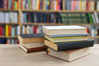 Kütüphanedeki ahşap masada yığınla kitap.