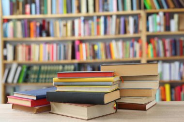 Kütüphanedeki ahşap masada yığınla kitap.