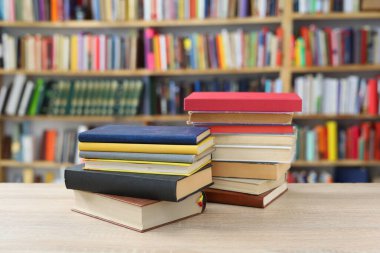 Kütüphane arkaplanına karşı ahşap masadaki kitap yığını