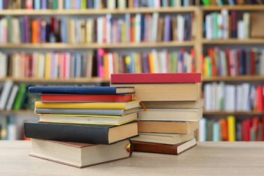Kütüphanedeki ahşap masada yığınla kitap.