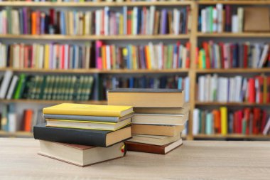 Kütüphanedeki ahşap raflarda yığınla kitap.