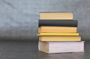 Kütüphanede bir yığın kitap, dünyanın en ünlü yazarlarının okumaya hazır güzel kitapları kütüphane arkaplanının önündeki ahşap masada yığınla kitap ve bardak. eğitim ve bilgi kavramı.