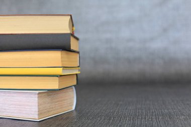 Kütüphanede bir yığın kitap, dünyanın en ünlü yazarlarının okumaya hazır güzel kitapları kütüphane arkaplanının önündeki ahşap masada yığınla kitap ve bardak. eğitim ve bilgi kavramı.