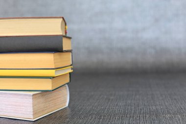 Kütüphanede bir yığın kitap, dünyanın en ünlü yazarlarının okumaya hazır güzel kitapları kütüphane arkaplanının önündeki ahşap masada yığınla kitap ve bardak. eğitim ve bilgi kavramı.