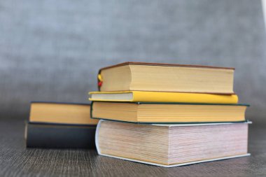 Kütüphanede bir yığın kitap, dünyanın en ünlü yazarlarının okumaya hazır güzel kitapları kütüphane arkaplanının önündeki ahşap masada yığınla kitap ve bardak. eğitim ve bilgi kavramı.