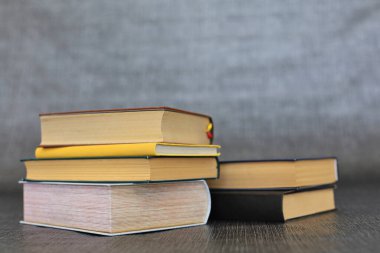 Kütüphanede bir yığın kitap, dünyanın en ünlü yazarlarının okumaya hazır güzel kitapları kütüphane arkaplanının önündeki ahşap masada yığınla kitap ve bardak. eğitim ve bilgi kavramı.