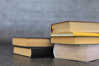 Kütüphanede bir yığın kitap, dünyanın en ünlü yazarlarının okumaya hazır güzel kitapları kütüphane arkaplanının önündeki ahşap masada yığınla kitap ve bardak. eğitim ve bilgi kavramı.