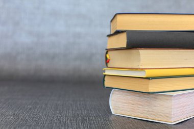 Kütüphanede bir yığın kitap, dünyanın en ünlü yazarlarının okumaya hazır güzel kitapları kütüphane arkaplanının önündeki ahşap masada yığınla kitap ve bardak. eğitim ve bilgi kavramı.