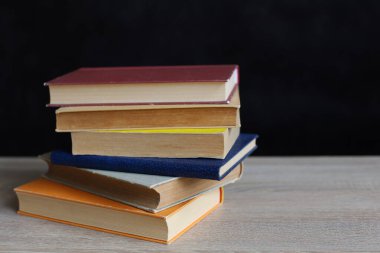 Kütüphanede bir yığın kitap, dünyanın en ünlü yazarlarının okumaya hazır güzel kitapları kütüphane arkaplanının önündeki ahşap masada yığınla kitap ve bardak. eğitim ve bilgi kavramı.