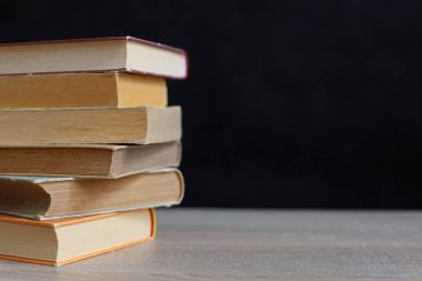 Kütüphanede bir yığın kitap, dünyanın en ünlü yazarlarının okumaya hazır güzel kitapları kütüphane arkaplanının önündeki ahşap masada yığınla kitap ve bardak. eğitim ve bilgi kavramı.