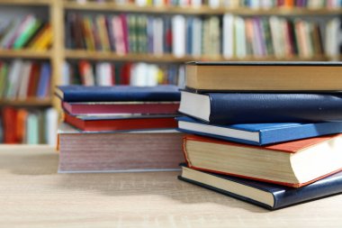 Kütüphanede bir yığın kitap, dünyanın en ünlü yazarlarının okumaya hazır güzel kitapları kütüphane arkaplanının önündeki ahşap masada yığınla kitap ve bardak. eğitim ve bilgi kavramı.