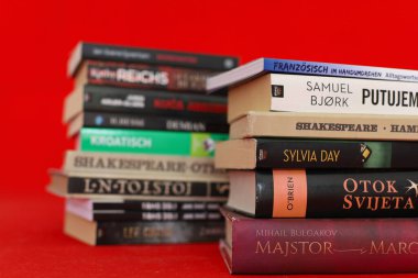 Masanın üzerinde farklı dillerin kırmızı kapağı olan kitaplar.