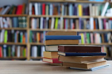 Kütüphanedeki ahşap masada yığınla kitap. Metin için boşluk