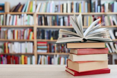 Kütüphanedeki ahşap masada yığınla kitap.