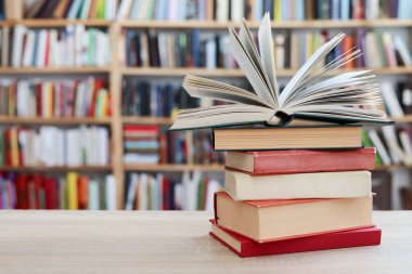 Ahşap masada yığınla kitap var.