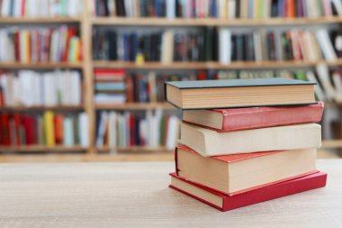 Kütüphanedeki ahşap masada yığınla kitap.