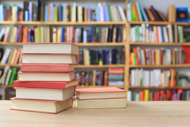 Kütüphane arkaplanındaki masadaki kitap yığını