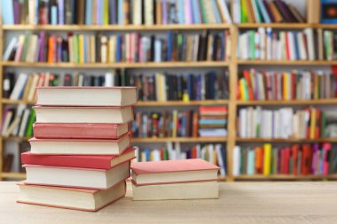 Kütüphanedeki ahşap masada yığınla kitap.