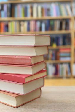 Kütüphanedeki ahşap masanın üzerine yığılmış kitap yığını, yakın çekim görünümü