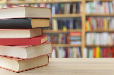 Kütüphanedeki ahşap masada yığınla kitap.