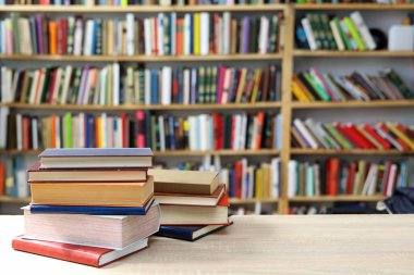 Kütüphanede masanın üstünde bir yığın kitap var.