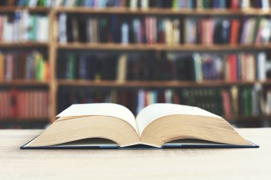 Kütüphanenin önündeki ahşap masada açık bir kitap, eğitim kavramı.