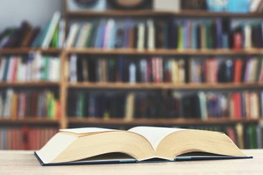 Kütüphanedeki ahşap masanın üzerinde bir yığın açık kitap