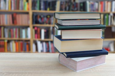 Kütüphanedeki ahşap masada yığınla kitap.