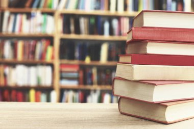 Kütüphanedeki ahşap masanın üzerinde kitap yığını