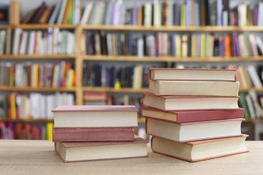Kütüphanedeki ahşap masada yığınla kitap.