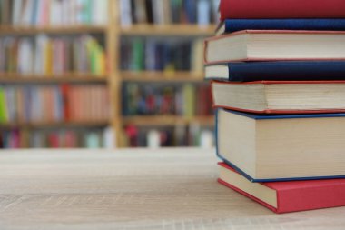 Kütüphanedeki ahşap masada yığınla kitap.