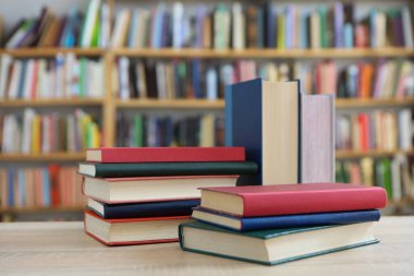 Kütüphanedeki ahşap masada yığınla kitap. Metin için boşluk