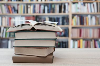 Ahşap masanın üzerinde bulanık arka plana karşı bir yığın kitap. Metin için boşluk