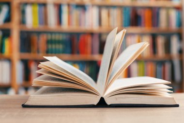 Kütüphanedeki ahşap masanın üzerinde kitaplar olan açık bir kitap.