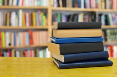 Kütüphanedeki ahşap masada yığınla kitap.