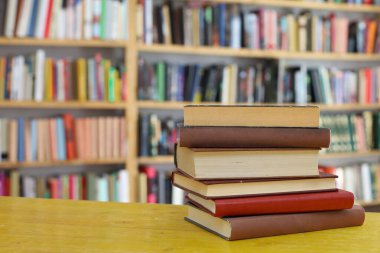 Kütüphanedeki ahşap masada yığınla kitap.