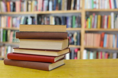 Kütüphanedeki ahşap masada yığınla kitap. Metin için boşluk
