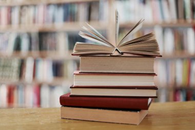 Kitaplar ve ahşap bir masanın üzerinde yığınla kitap.