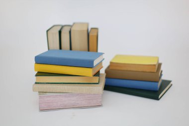 Beyaz arka plan üzerine bir yığın kitap, dünyanın en ünlü yazarlarının okumaya hazır güzel kitapları, kütüphane arkaplanının önündeki ahşap masanın üzerinde bir yığın kitap ve gözlük. eğitim ve bilgi kavramı, kütüphane, okul