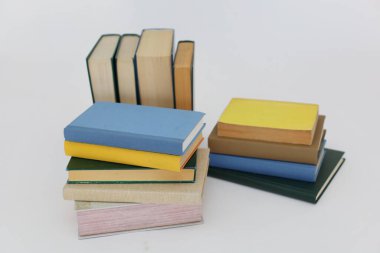 Beyaz arka plan üzerine bir yığın kitap, dünyanın en ünlü yazarlarının okumaya hazır güzel kitapları, kütüphane arkaplanının önündeki ahşap masanın üzerinde bir yığın kitap ve gözlük. eğitim ve bilgi kavramı, kütüphane, okul