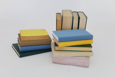 Beyaz arka plan üzerine bir yığın kitap, dünyanın en ünlü yazarlarının okumaya hazır güzel kitapları, kütüphane arkaplanının önündeki ahşap masanın üzerinde bir yığın kitap ve gözlük. eğitim ve bilgi kavramı, kütüphane, okul