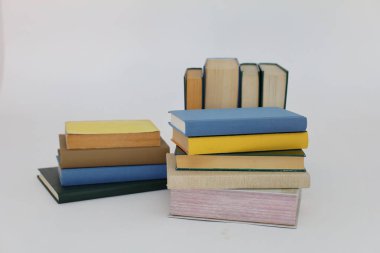 Beyaz arka plan üzerine bir yığın kitap, dünyanın en ünlü yazarlarının okumaya hazır güzel kitapları, kütüphane arkaplanının önündeki ahşap masanın üzerinde bir yığın kitap ve gözlük. eğitim ve bilgi kavramı, kütüphane, okul