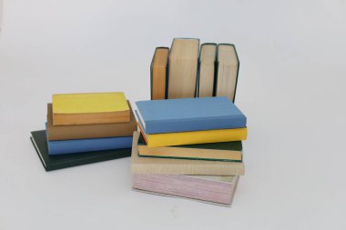 Beyaz arka plan üzerine bir yığın kitap, dünyanın en ünlü yazarlarının okumaya hazır güzel kitapları, kütüphane arkaplanının önündeki ahşap masanın üzerinde bir yığın kitap ve gözlük. eğitim ve bilgi kavramı, kütüphane, okul