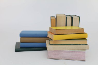 Beyaz arka plan üzerine bir yığın kitap, dünyanın en ünlü yazarlarının okumaya hazır güzel kitapları, kütüphane arkaplanının önündeki ahşap masanın üzerinde bir yığın kitap ve gözlük. eğitim ve bilgi kavramı, kütüphane, okul