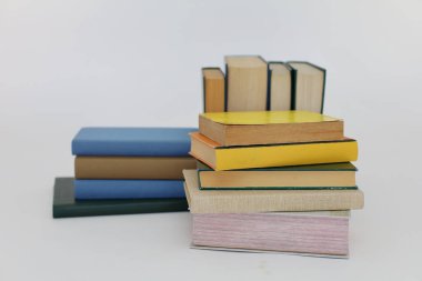 Beyaz arka plan üzerine bir yığın kitap, dünyanın en ünlü yazarlarının okumaya hazır güzel kitapları, kütüphane arkaplanının önündeki ahşap masanın üzerinde bir yığın kitap ve gözlük. eğitim ve bilgi kavramı, kütüphane, okul